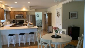 A modern kitchen with wooden cabinets, stainless steel appliances, and a central island with bar stools. - Clean, Spacious Family House (Annapolis)