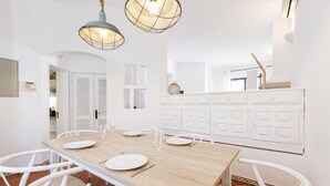 A dining area with a wooden table, white chairs, and pendant lights. - CASAS DA PRAIA JOANA (Almancil)