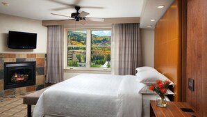 A hotel room with a large bed, a fireplace, a TV mounted on the wall, and a view of the outdoors. - Awesome Two-Bedroom Villa - New Year’s Week - Sheraton Mountain Vista (Avon)
