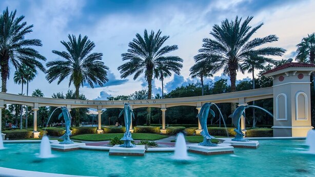 Una piscina con varias fuentes y palmeras al fondo.