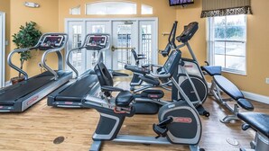 Un gimnasio con cintas de correr, elípticas y una banca.