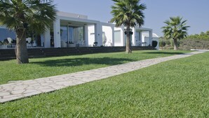 A modern house with a paved pathway, palm trees, and a clear sky. - ktima reveli luxury villa (χανια καλαθας)