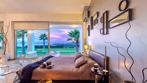 A modern bedroom with a large bed, a view of the outdoors, and a minimalist decor. - ktima reveli luxury villa (χανια καλαθας)
