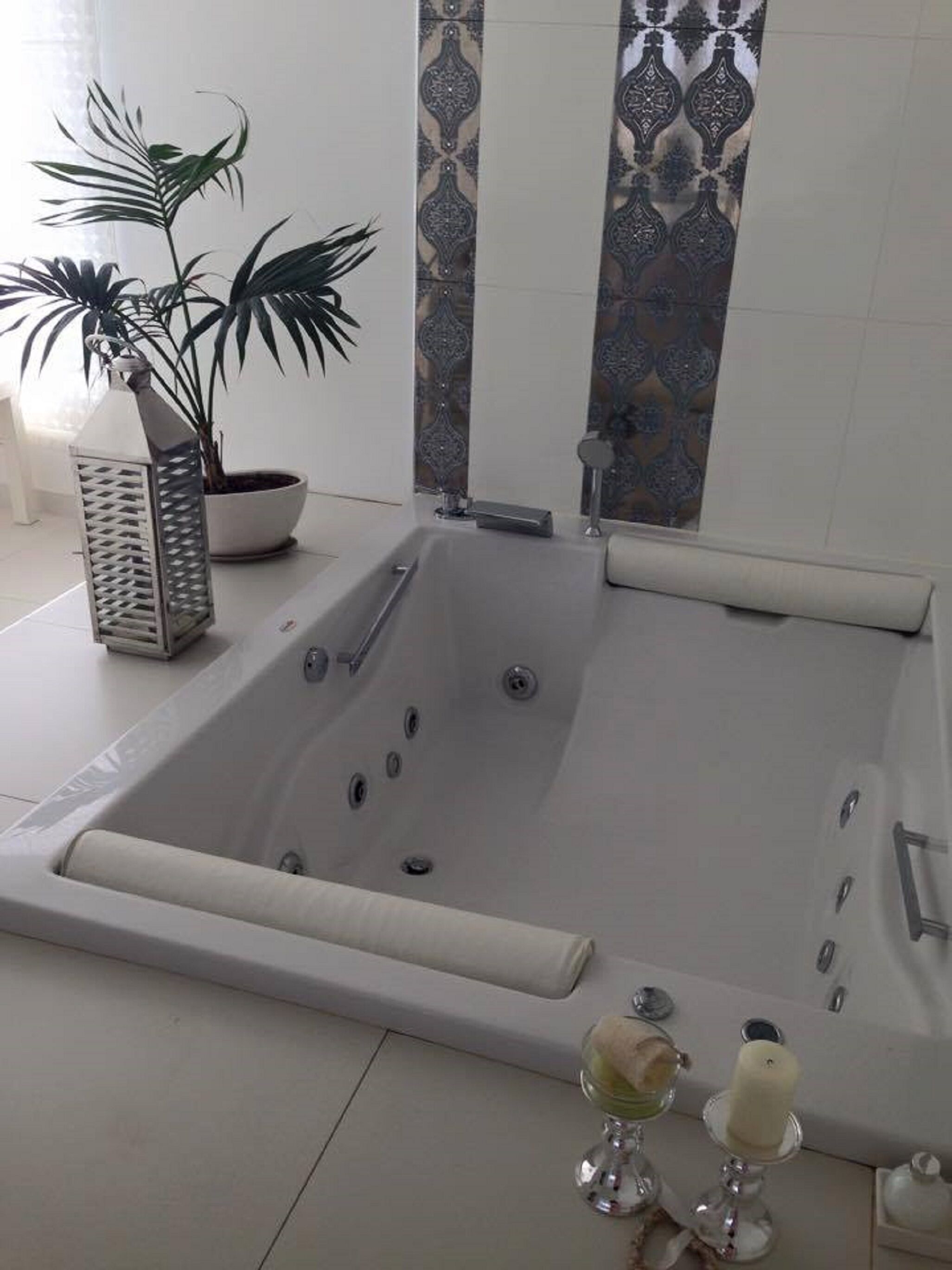 Un bagno moderno con una vasca da bagno indipendente, una pianta in vaso e una grattugia metallica decorativa.