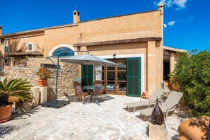 Une terrasse en pierre avec des meubles d’extérieur, une table et des chaises.
