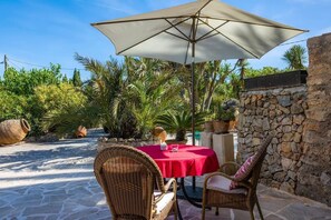 An outdoor patio with a table and chairs, a large umbrella, and potted plants. - Studio SUR, 35 square meters (Son Macia)
