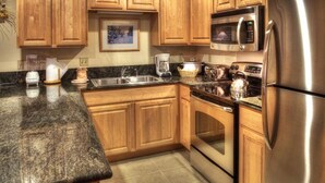 A kitchen with wooden cabinets, a stainless steel refrigerator, a microwave, a toaster, and a kettle.