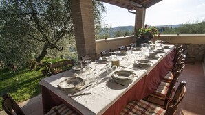 A long dining table set outdoors with chairs, a view of greenery and hills in the background. - Il Poggio dell'Artilla, an oasis of peace to relax and regenerate (castiglione in teverina  (VT) Lazio)