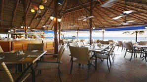 Un restaurant en plein air avec des tables et des chaises, un coin bar et une vue sur la plage.