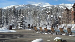 A resort with outdoor seating, snow-covered trees, and mountains in the background. - One Bedroom Master Unit. Beautiful Luxury Ski in, Ski Out Resort (Breckenridge)