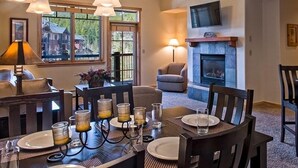 A dining area with a table set for four, a fireplace, and a television mounted on the wall. - One Bedroom Master Unit. Beautiful Luxury Ski in, Ski Out Resort (Breckenridge)