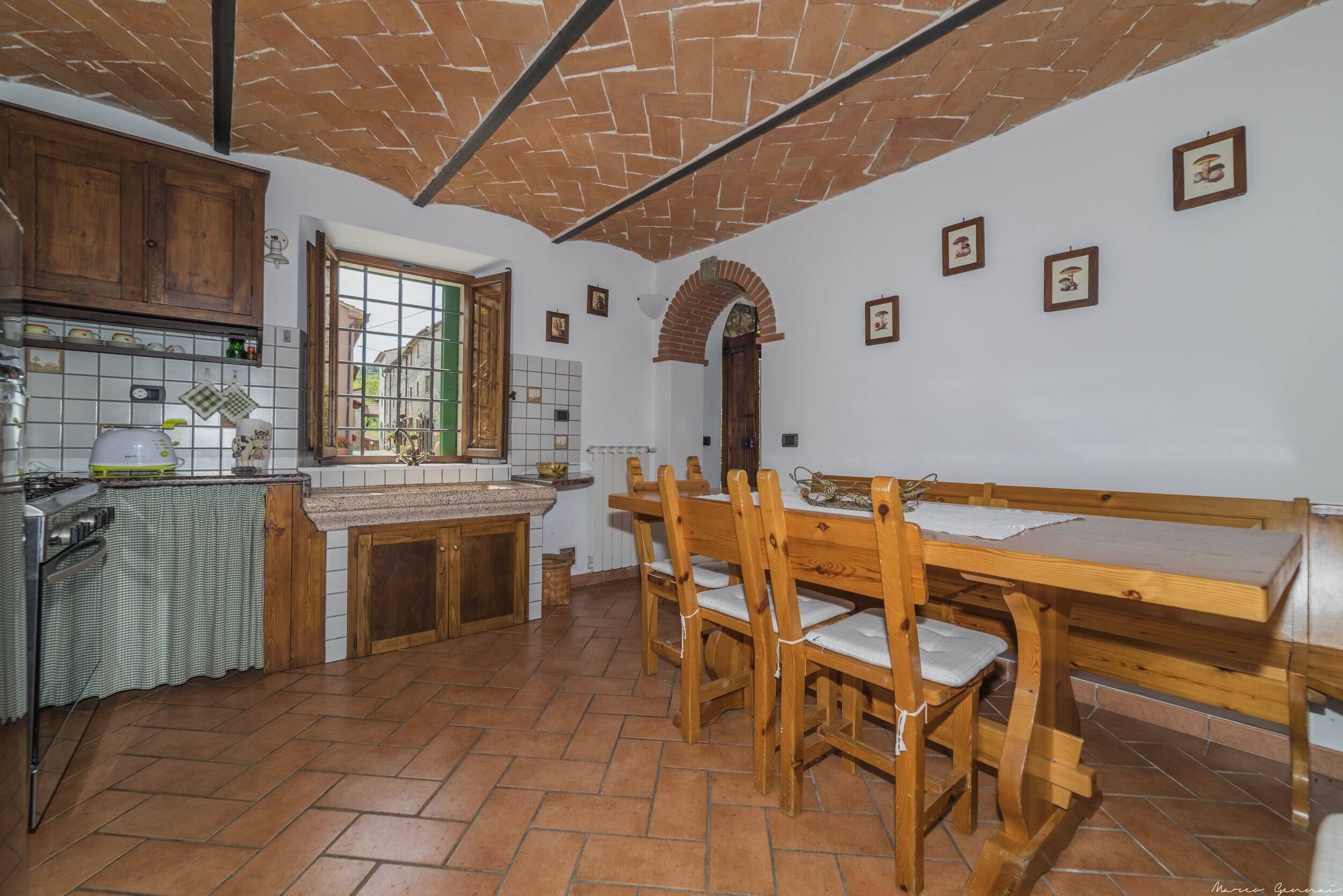 A kitchen with a wooden table and chairs, a stove, and a window with a view of buildings.