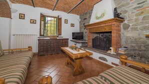 Un salón acogedor con chimenea, televisor y pared de piedra.