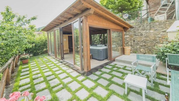 Un patio exterior moderno con jacuzzi, escalones de piedra y mobiliario de madera.