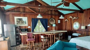 A rustic cabin-style room with a kitchenette, a dining area, and a bed.