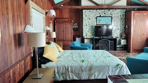 A wooden room with a bed, a TV, a fireplace, and a blue chair.