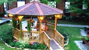 A wooden gazebo with a tiled roof, surrounded by a garden with various plants and a bench. - 2br Condo Re-modeled Great Smokey Mountains Dollywood Old Mill July 4th (Pigeon Forge)