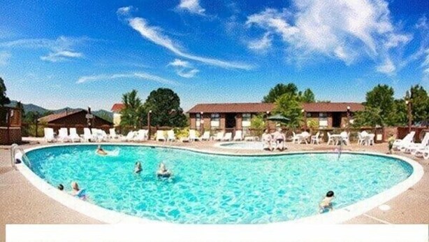 A swimming pool surrounded by lounge chairs and a building with a red roof. - 2br Condo Re-modeled Great Smokey Mountains Dollywood Old Mill July 4th (Pigeon Forge)