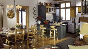 Una sala de estar amplia con comedor, una cocina con isla central y una escalera que conduce a un nivel superior.