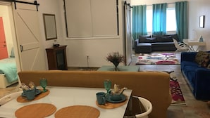Un comedor con una mesa preparada para dos personas, un sofá y un diván en una sala de estar.