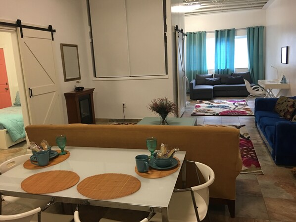 A dining area with a table set for two, a sofa, and a couch in a living room.