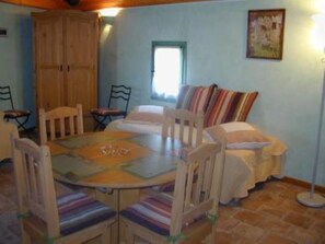 A cozy room with a round table, chairs, a sofa, and a window. - Montaren Et Saint Mediers: LODGING BAMBOO apartment in Farmhouse of the XVIIIème century with mezzanine, made safe heated swimming pool and Spa (Montaren-Et-Saint-Médiers)