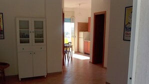 Ein Flur mit einem weißen Schrank, ein Essbereich mit Stühlen und eine Küche mit Schränken.