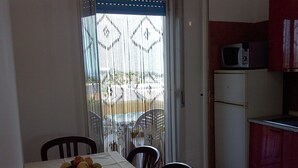 Ein Essbereich mit einem für zwei gedeckten Tisch, einer Obstschale und Blick durch eine verzierte Tür.