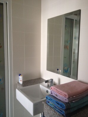 Un bagno con lavandino, specchio e pile di asciugamani.
