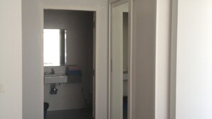 A hallway with a wooden floor, a door leading to a bathroom, and a white wardrobe. - Nice 1- Bedroom Condo In Klong Muang (Klong Muang)