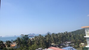 A coastal view with a clear sky, palm trees, and a distant mountain range. - Nice 1- Bedroom Condo In Klong Muang (Klong Muang)