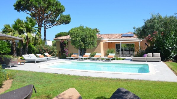 A pool area with lounge chairs, a house with a tiled roof, and surrounding greenery. - Master Suite Villa featuring a Private Pool, Garden, Parking and Spa (CALVI)