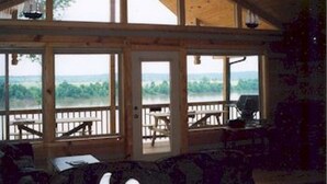 Eine Hütte mit großen Fenstern, die einen Blick auf See und Wald freigibt.