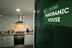 A modern kitchen with a marble backsplash, stainless steel appliances, and a visible bottle on the counter.