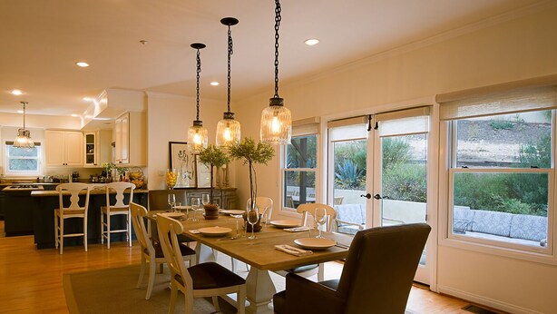 A spacious dining area with a long table, multiple chairs, and pendant lighting.