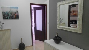 A hallway with a white radiator, a black vase on a white counter, and a mirror with a decorative frame.