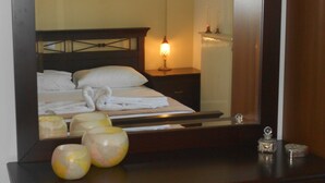 A hotel room with a bed, a nightstand, a mirror, and decorative items on the dresser.