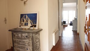 A hallway with a decorative wall piece, a white radiator, and a tiled floor. - Two bedroom apartment with sea views (Ampuriabrava)