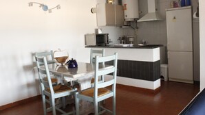 A kitchen with a dining table and chairs, a microwave, a stove, and a refrigerator. - Two bedroom apartment with sea views (Ampuriabrava)