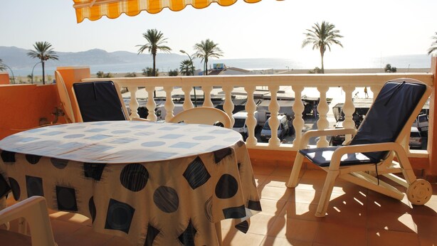 A round table with a patterned tablecloth, two chairs, and a yellow-striped umbrella. - Two bedroom apartment with sea views (Ampuriabrava)