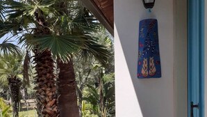 Un sentiero conduce a un edificio con una porta blu, un lanterna a parete e una palma.