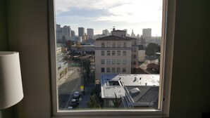 Une vue depuis une fenêtre d’un immeuble, avec un paysage urbain en arrière-plan, comprenant des gratte-ciel et une rue avec des voitures.