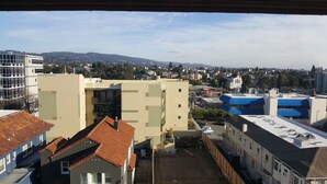 Une vue sur un paysage urbain avec des bâtiments, notamment un immeuble à plusieurs étages doté de balcons et un bâtiment avec un toit bleu.