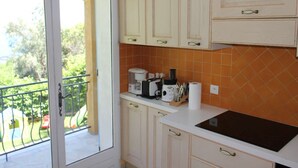 Una cocina con gabinetes blancos, encimera negra y salpicadero con azulejos naranja.