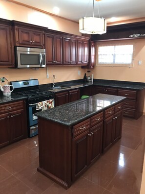 Una cocina moderna con armarios de madera oscura, electrodomésticos de acero inoxidable y una isla con encimera de granito.