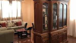 Uma sala de estar com um armário de madeira, um sofá, uma mesa de centro e um ventilador de teto.