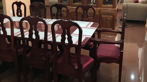 Uma área de refeições com uma mesa e cadeiras de madeira, um armário com portas de vidro e um ventilador de teto.