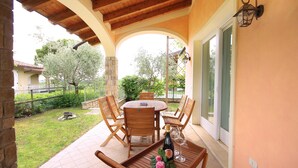 Eine Terrasse im Freien mit einem runden Holztisch und Stühlen, einer Weinflasche und einem Glas auf dem Tisch.