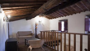 Een gezellige woonkamer met een houten plafond, een bank, een tafel en een stoel.