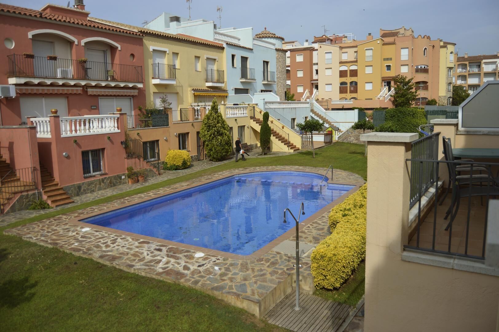 Une piscine entourée d’une terrasse en pierre, avec une personne à proximité.